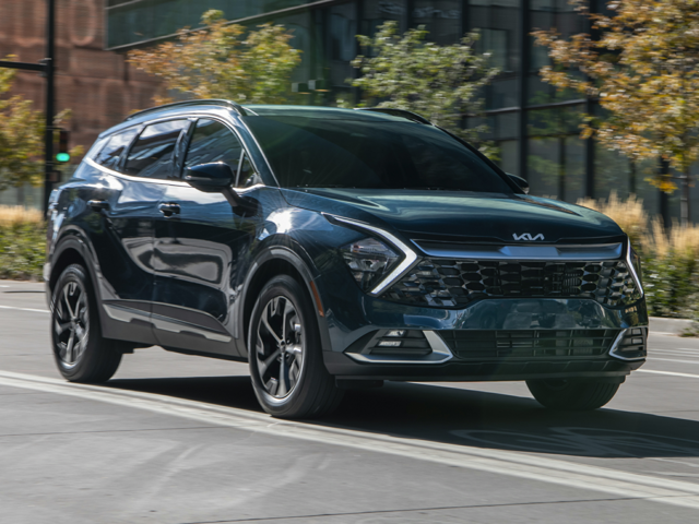 An image of a blue Kia Sportage Hybrid driving down a country road.