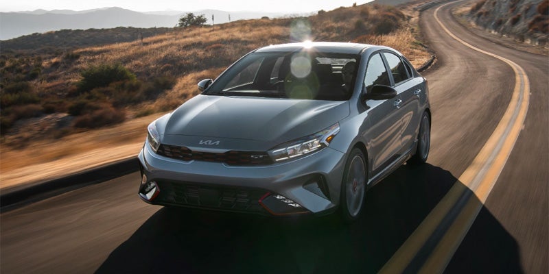 An image of a gray Kia Forte tackling a winding highway road. 