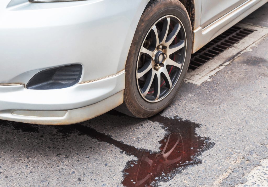 An image of a car leaking transmission fluid onto the pavement.