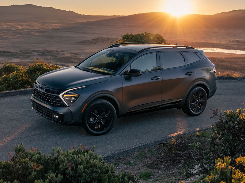 a black 2026 Kia Sportage Hybrid SUV is parked near Shiloh, IL with a sunset in the background